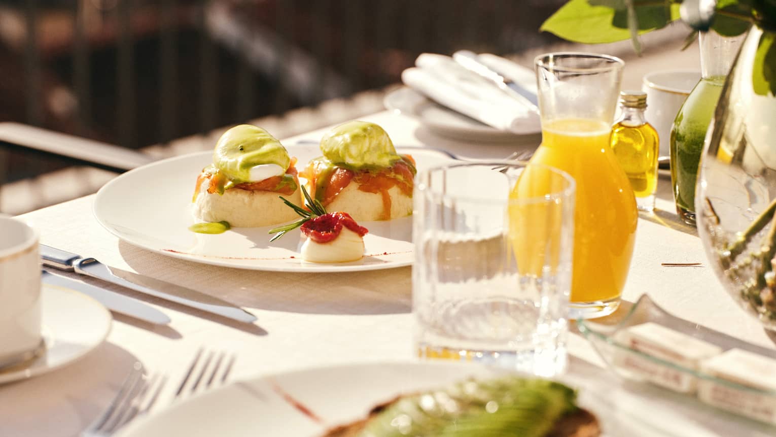 White plates topped with colourful brunch dishes on a table with glasses and a carafe filled with orange juice
