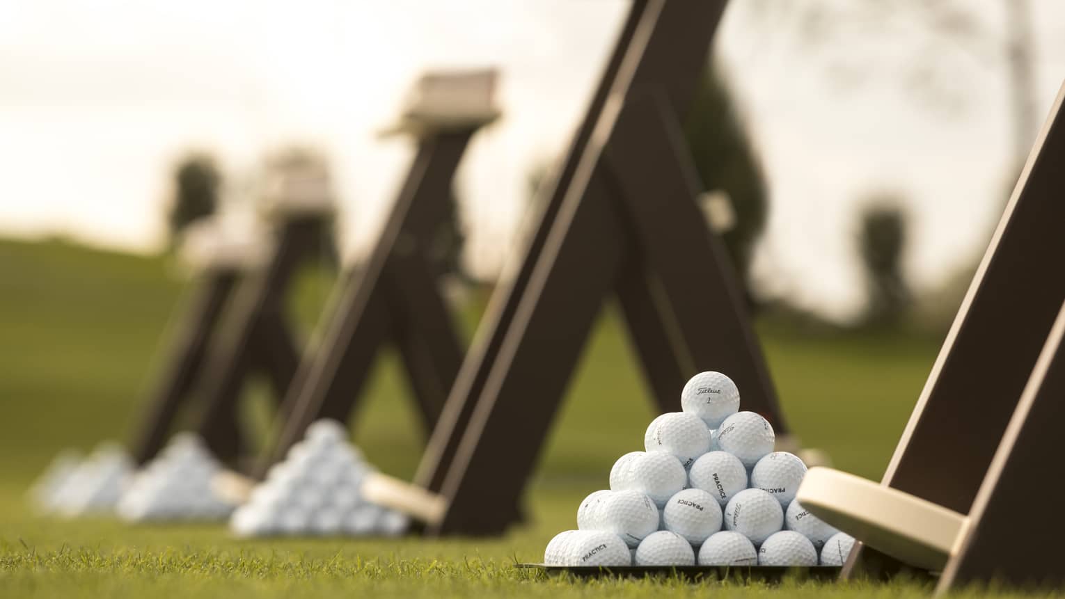 Stacks of white golf balls on lawn in front of wood panels
