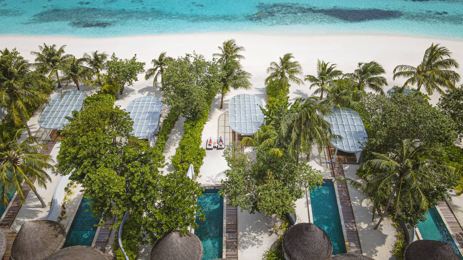 Aerial view of beachfront villas with pools at luxury tropical resort
