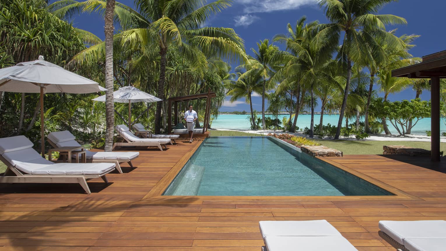 Villa's private pool with a lagoon view, surrounded by a wooden deck with sun chairs