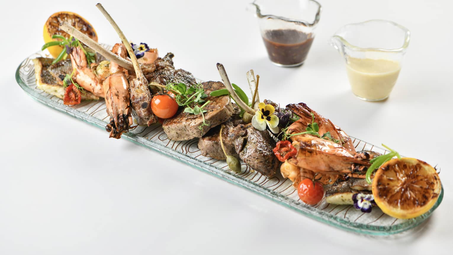 Surf and turf platter featuring Jumbo prawns, seabass, beef tenderloin, lamb chops, served with potato pur�e, saut�ed mushroom, grilled vegetables, citrus cream and an herbs sauce