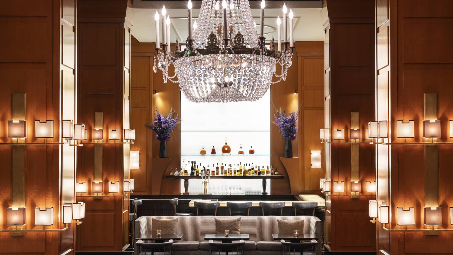A bar area with a large chandelier and small lights on the walls.