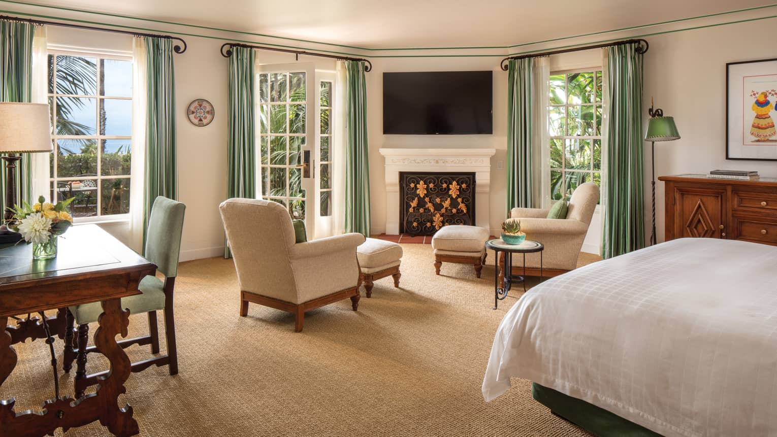 Ocean-View Room two white armchairs around fireplace mantle, TV, white French doors, green curtains