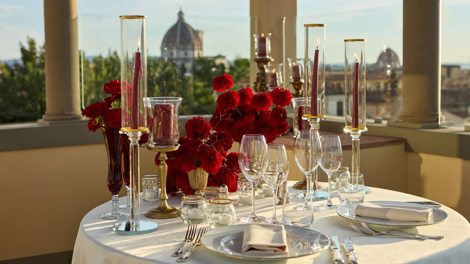 Terrace with elegant, romantic table set for two with crystal glassware and candlesticks looking out to the Duomo