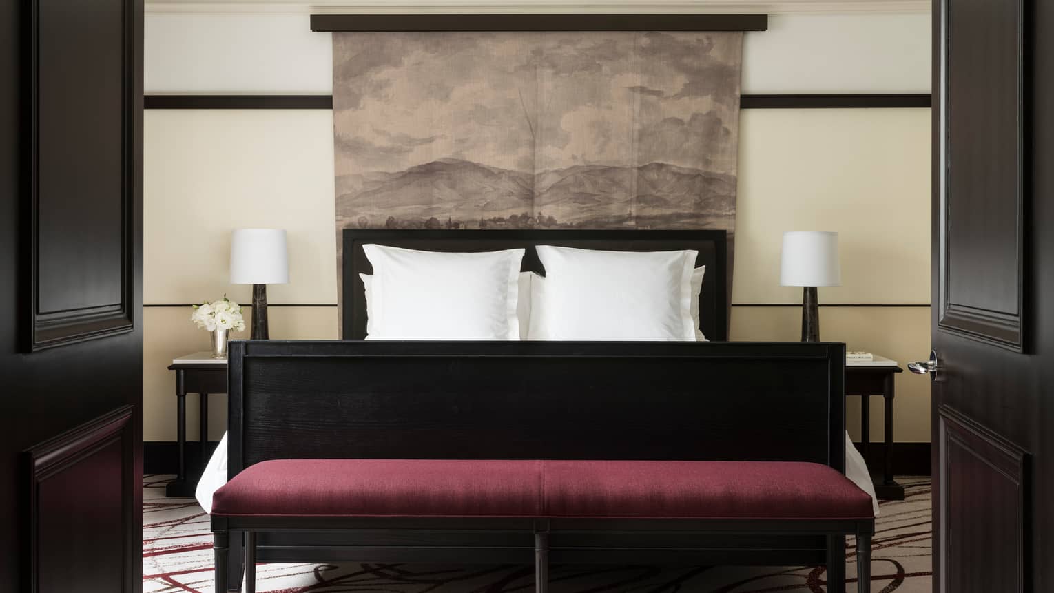 Open black French doors revealing Executive Suite bed, burgundy velvet bench at foot