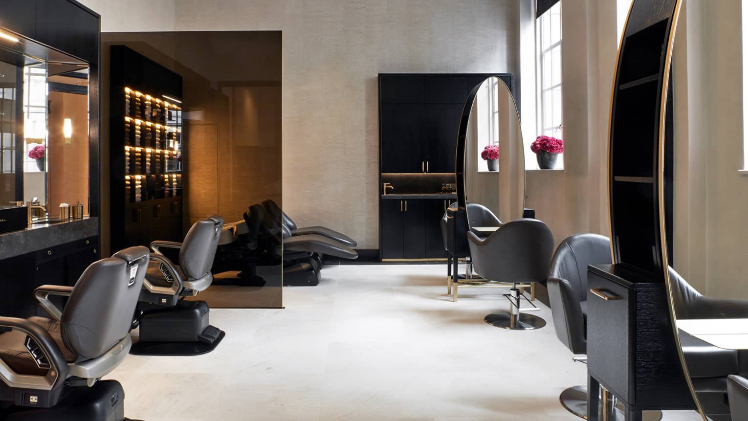 A spacious salon space with soft natural light from large windows, and decor in serene neutral hues