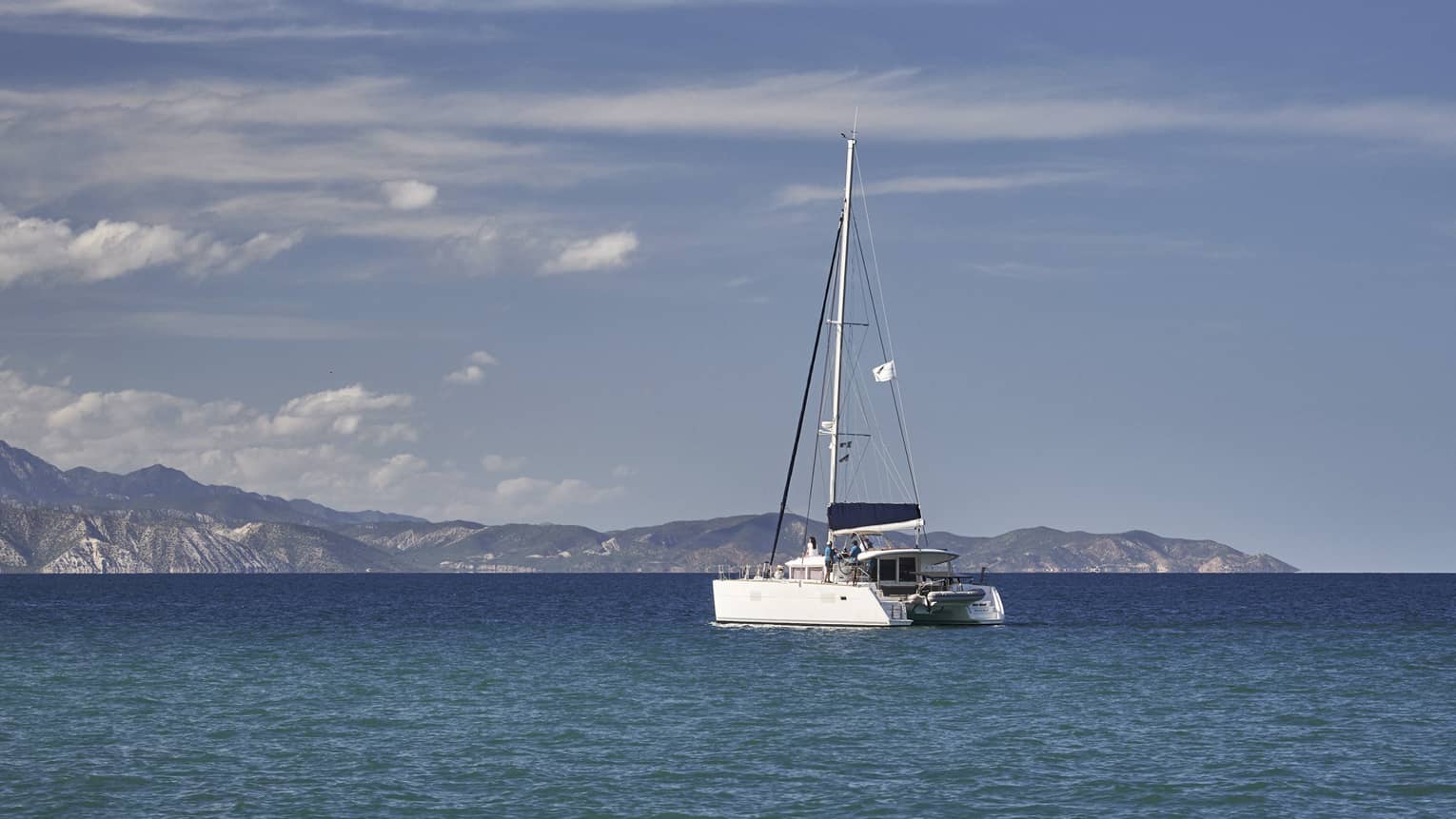 A boat sailing on the ocean with mountains in the distance.