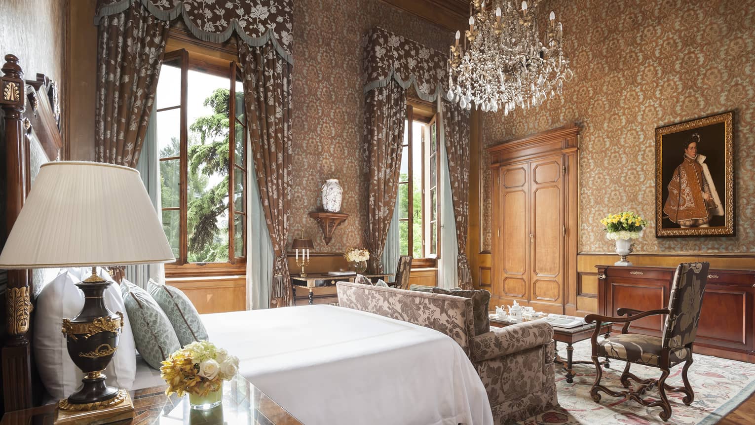 Gallery suite bedroom with king bed, crystal chandelier, high ceilings, and rich wood and floral furnishings at Four Seasons Hotel Florence