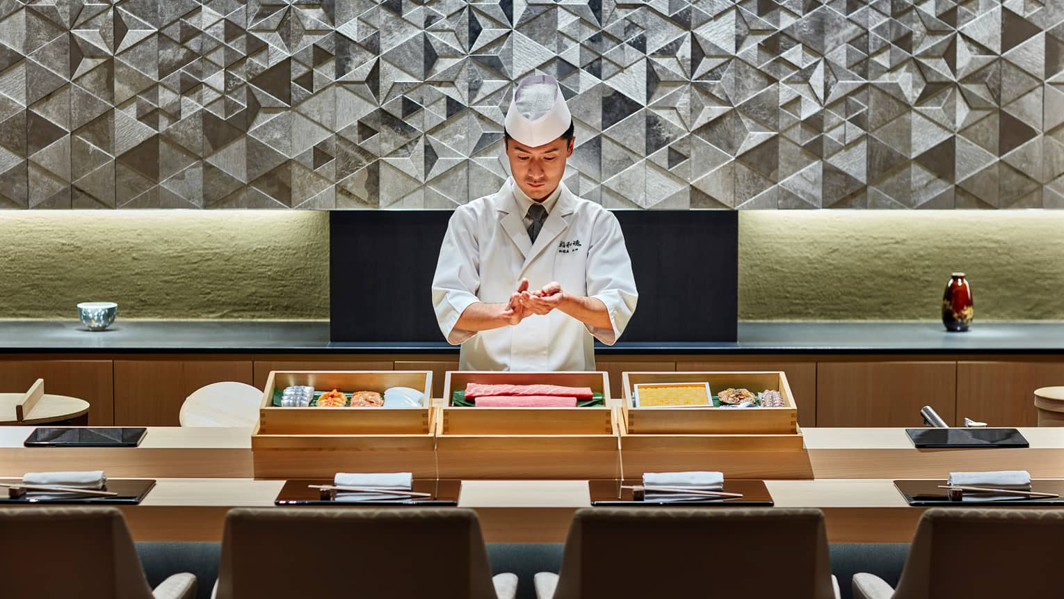 Sushi chef prepares fish behind bamboo display, Sushi wakon bar