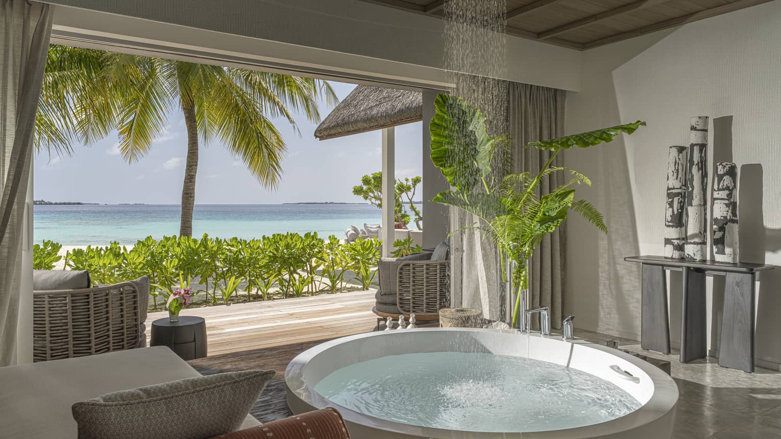 Large luxury bathroom with a circular tub opening to a tropical beachfront deck