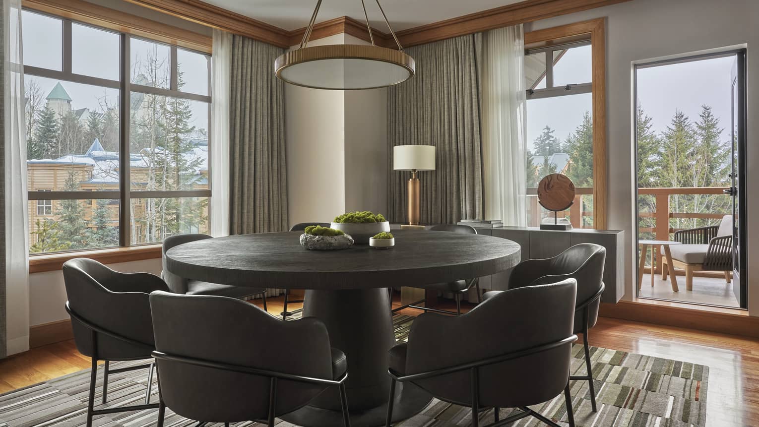 Round dining table with six modern, leather seats and a door leading out to a balcony