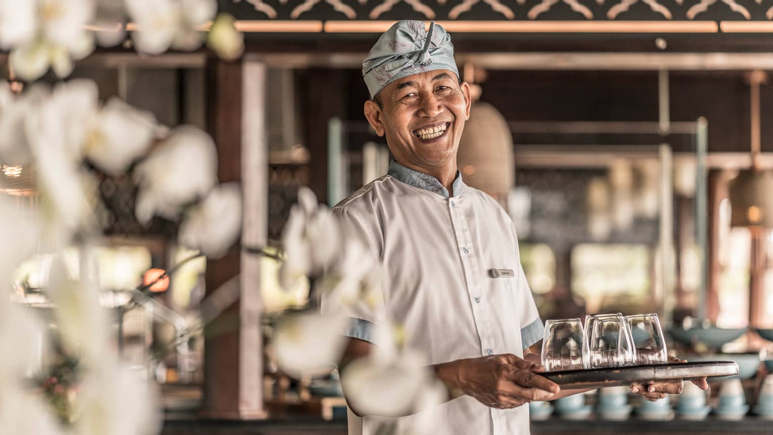 Smiling chef holds tray with glasses 