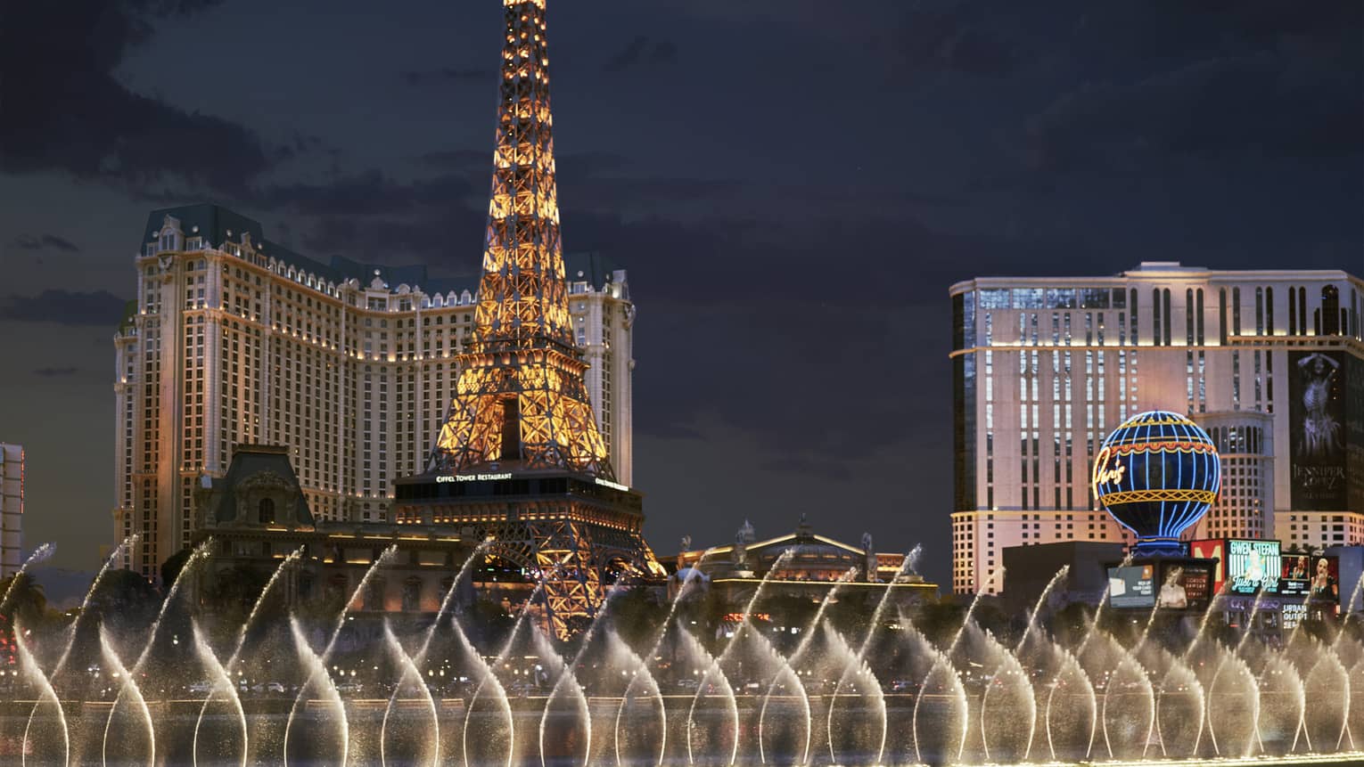 Las Vegas strip with Eiffel Tower, row of fountains and lights at night
