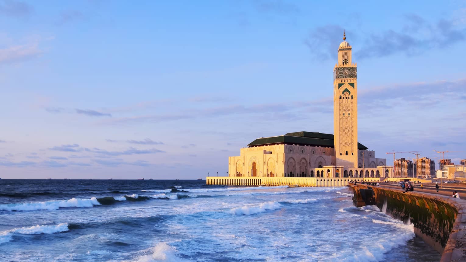 Aside rolling waves stands a golden mosque with domed archways carved into all sides and a towering minaret with a domed top.