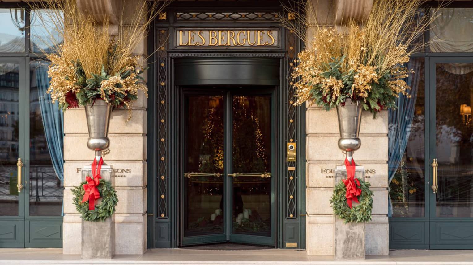 The doors to a hotel with wreaths next to them.