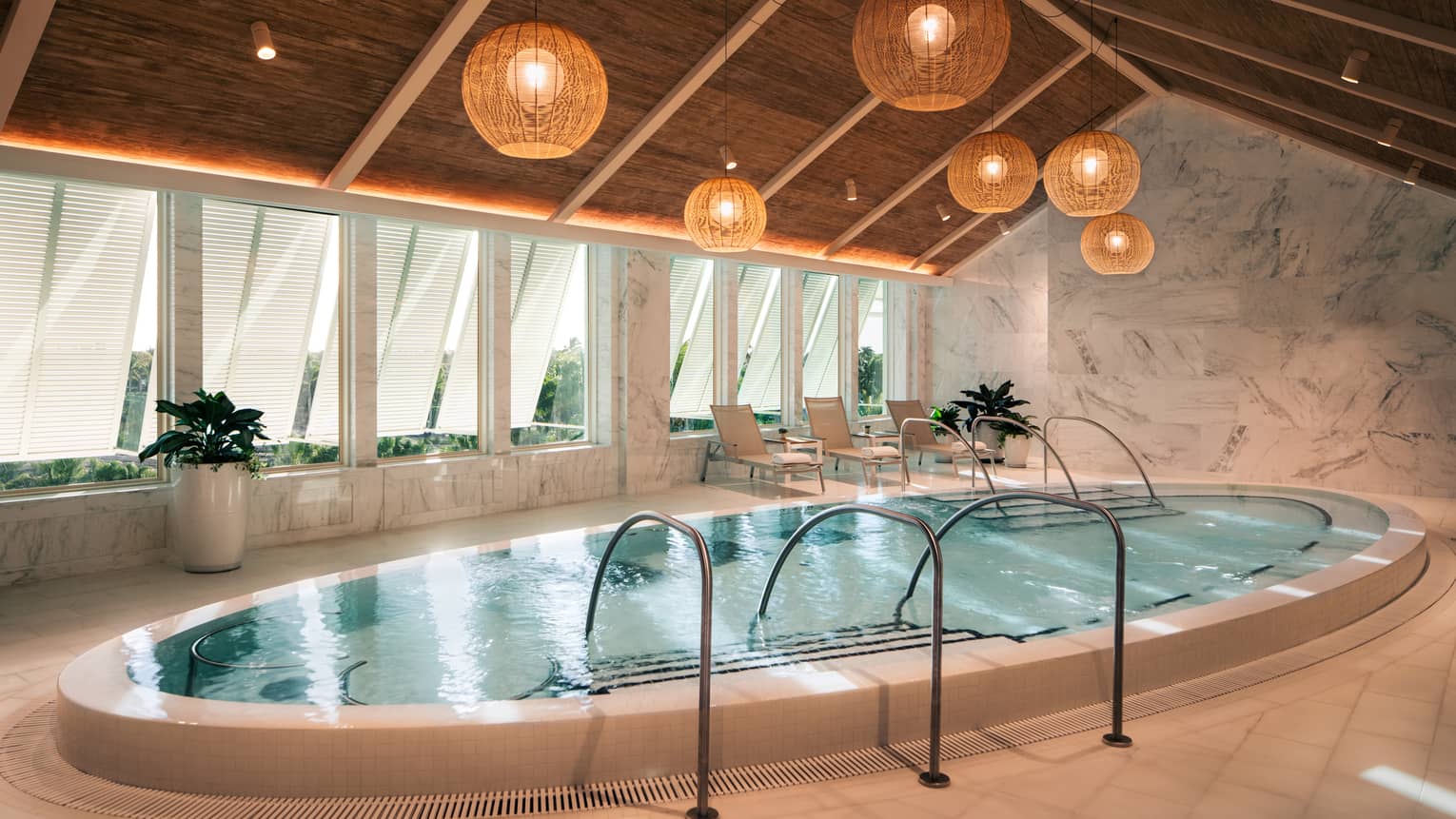 Large oblong whirlpool set beneath a tall peaked ceiling with rattan lanterns hanging in the centre