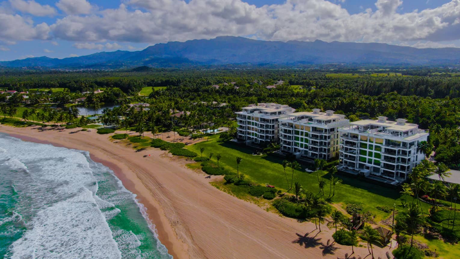 Aerial view of residences building, beach and ocean with mountains in the background