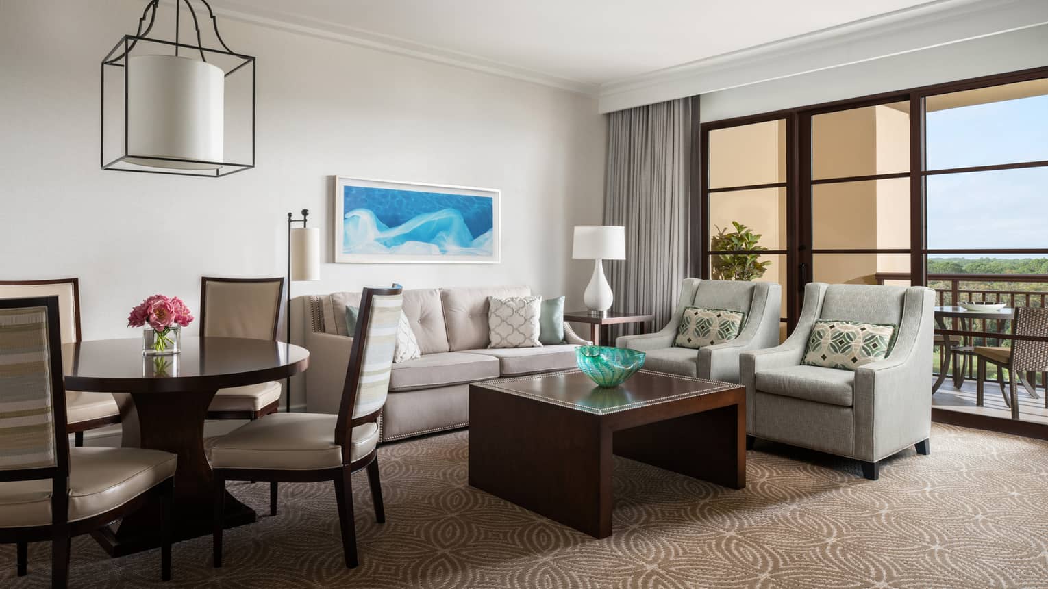 Living room with beige sofa, two arm chairs, wooden coffee table, round dining table and four chairs