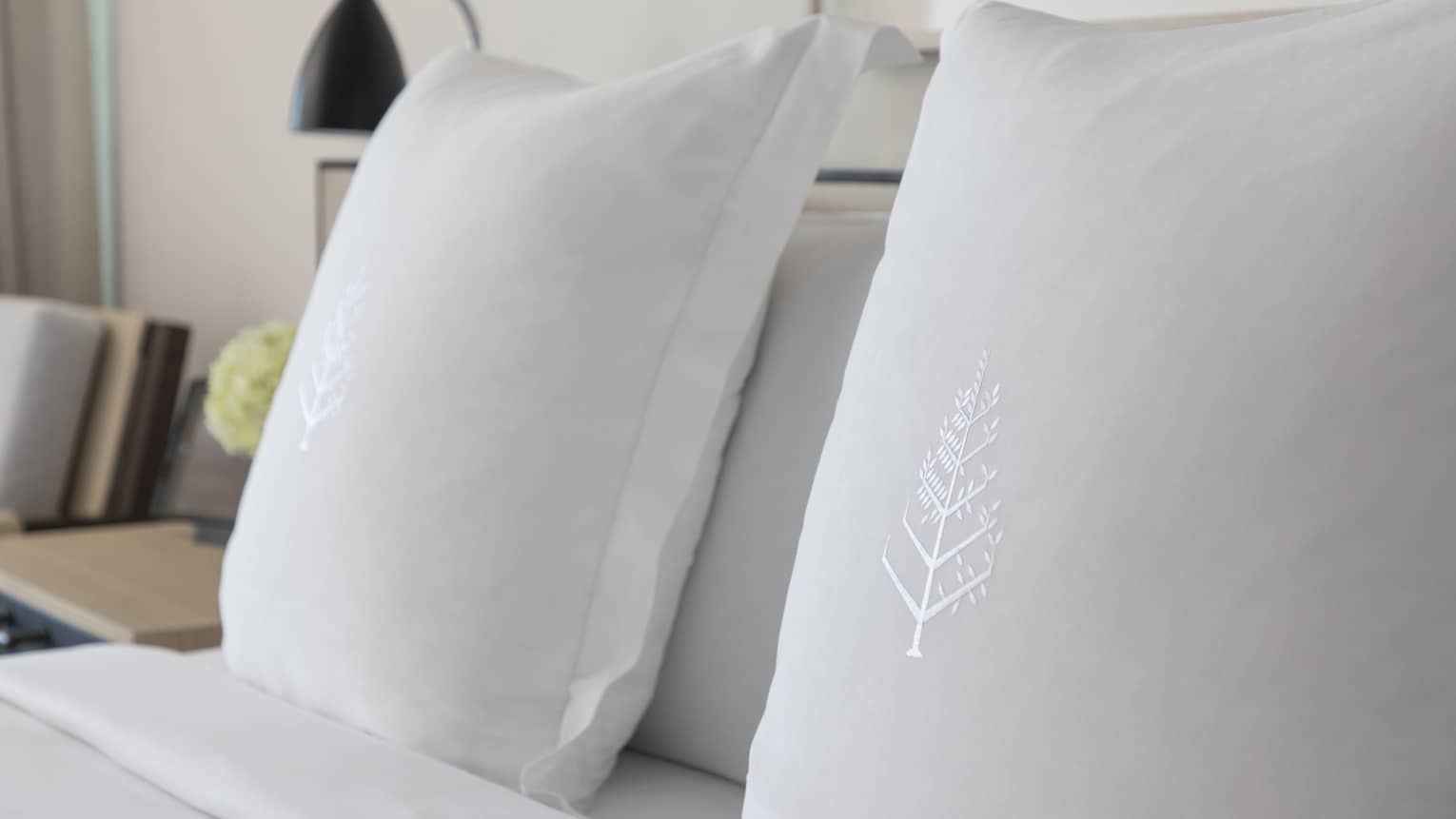 Two white sham pillows on bed with embroidered Four Seasons logos