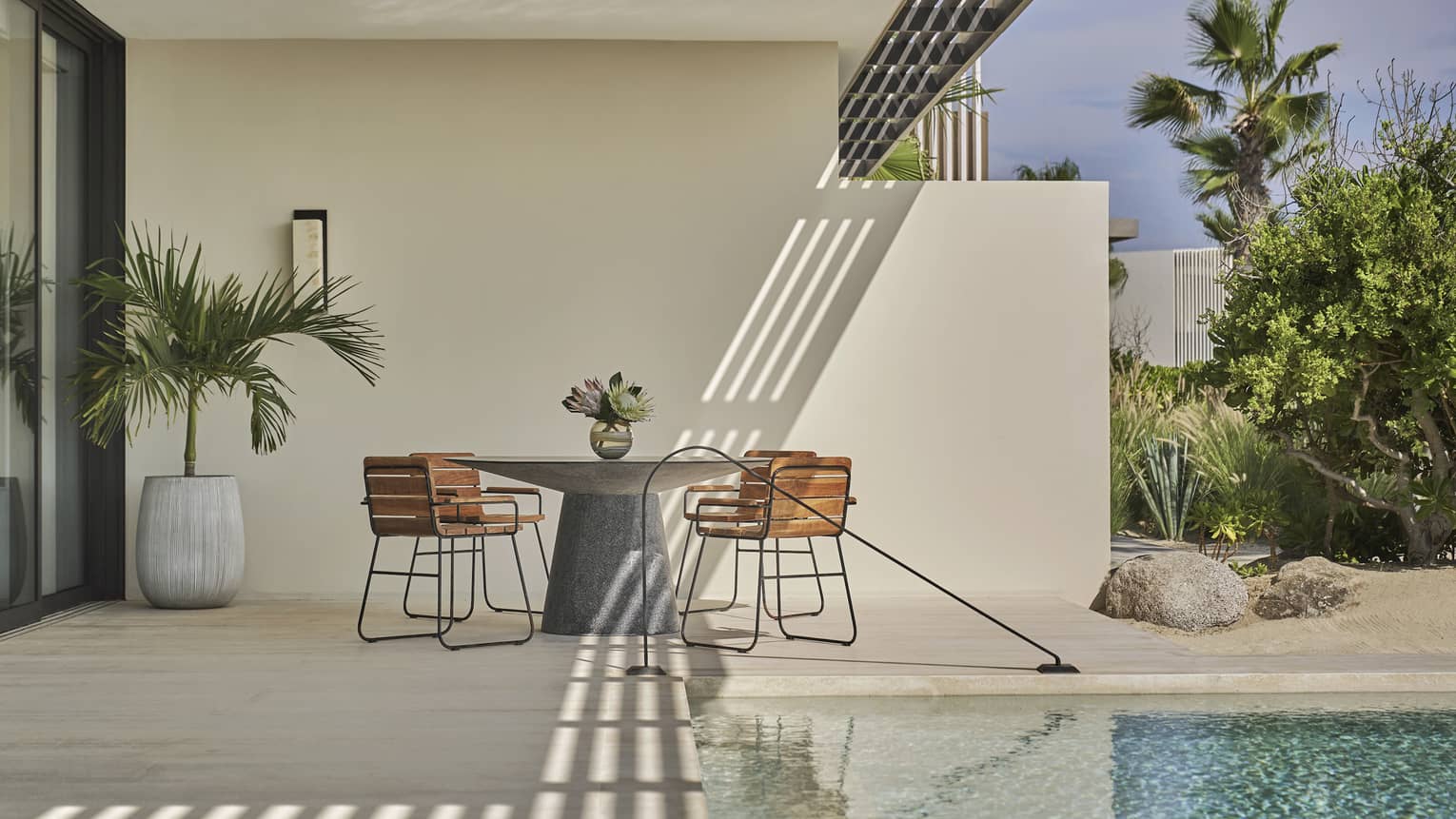 Two Bedroom Sunrise Suite pool with round table, four chairs, potted palm