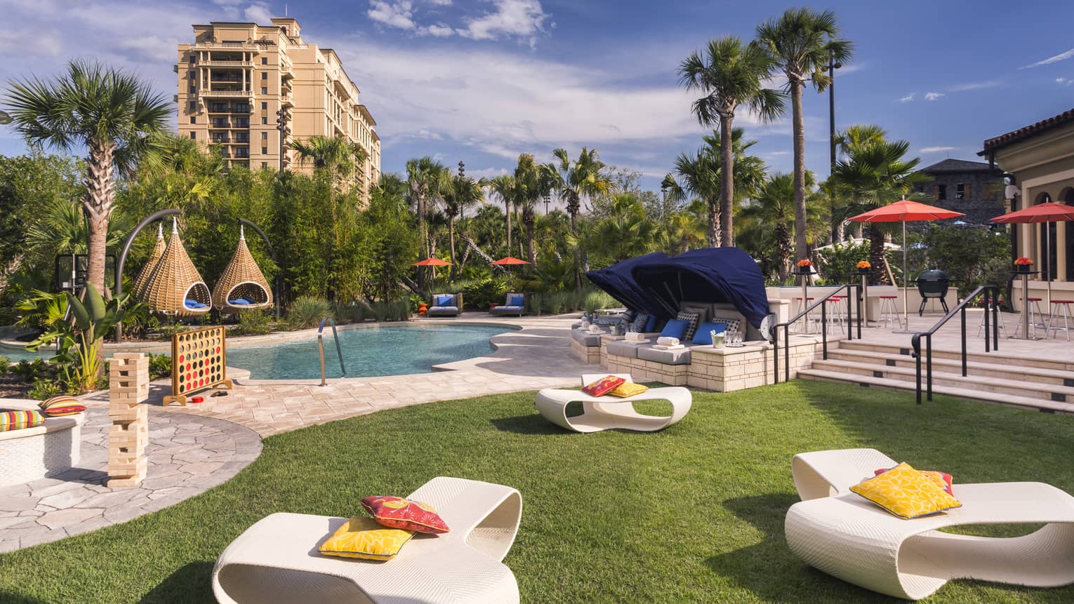 White patio chairs, hanging baskets, palm trees around swimming pool deck