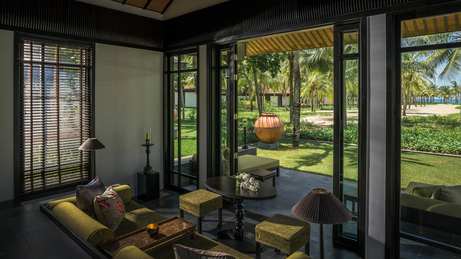 Pool Villa living room with green velvet sofa, stool, high ceilings, open patio wall
