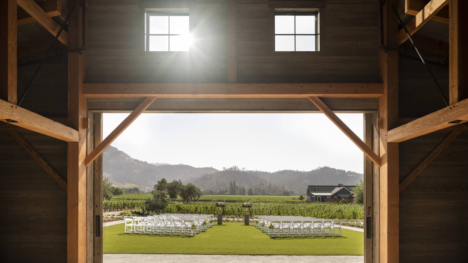 Barn doors opening up to lawn set up for wedding ceremony