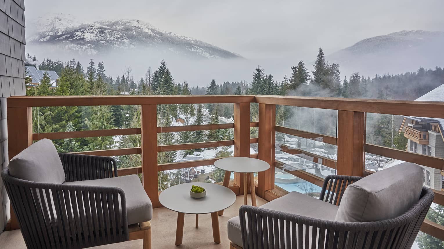 Balcony with two arm chairs and small tables, overlooking Whistler mountains