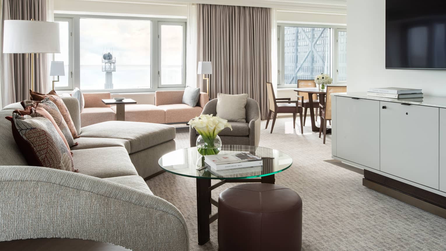 Living room with curved sofa, glass coffee table, TV, carpeting, opening to the dining area