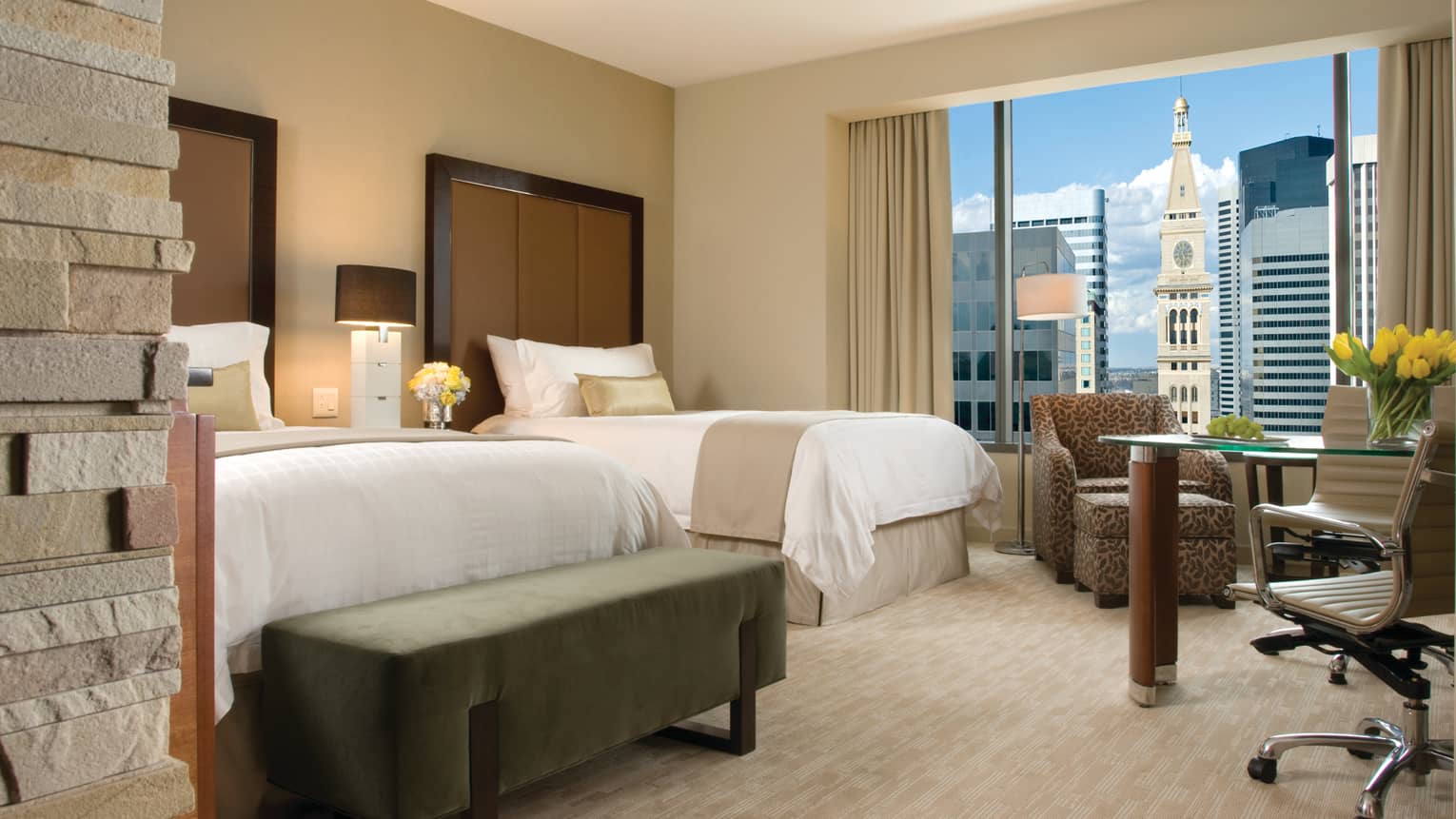 Deluxe Room stone accent wall, double beds, armchair, desk by window