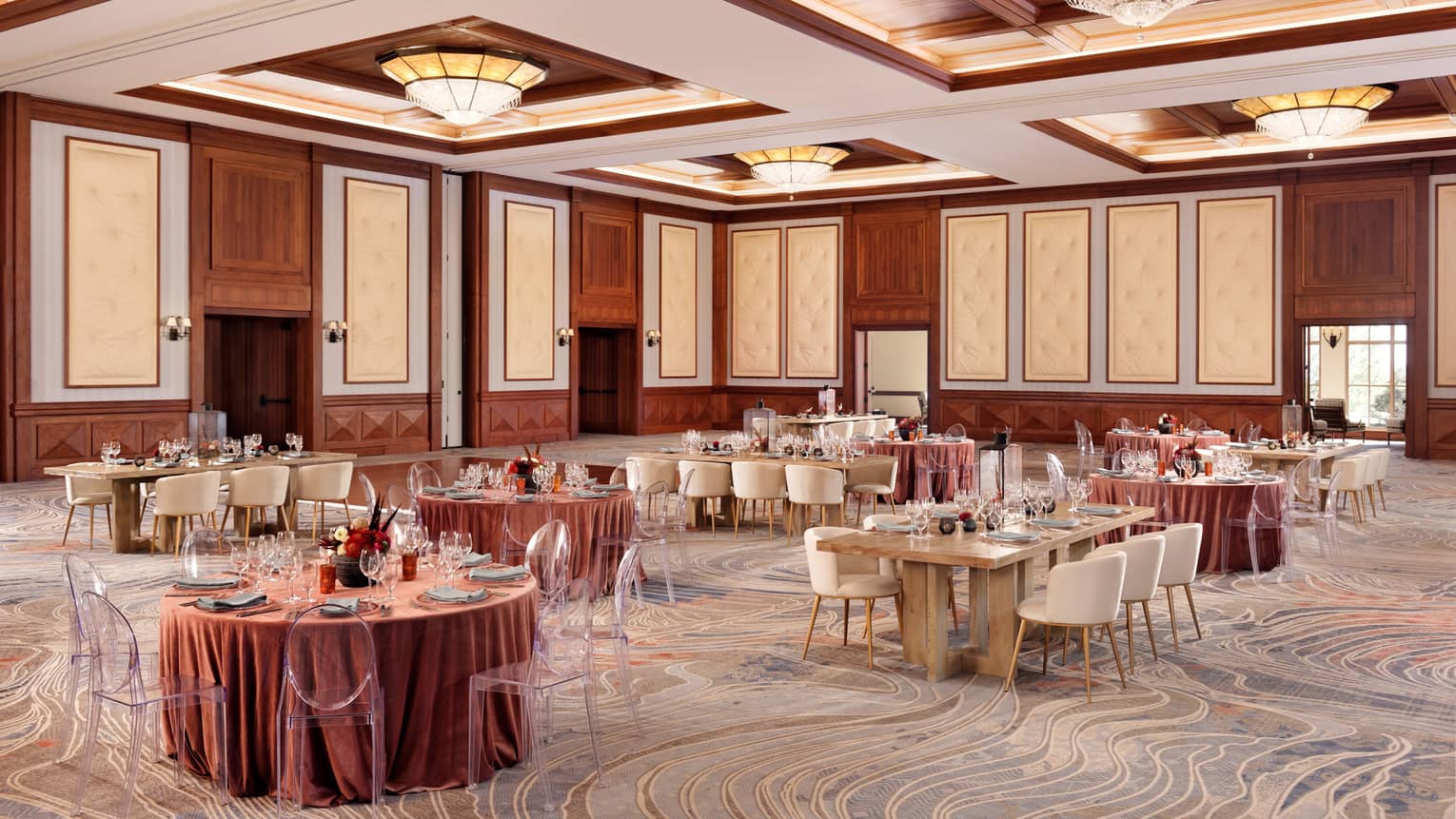 A room with large round and rectangular tables covered in pink cloth.