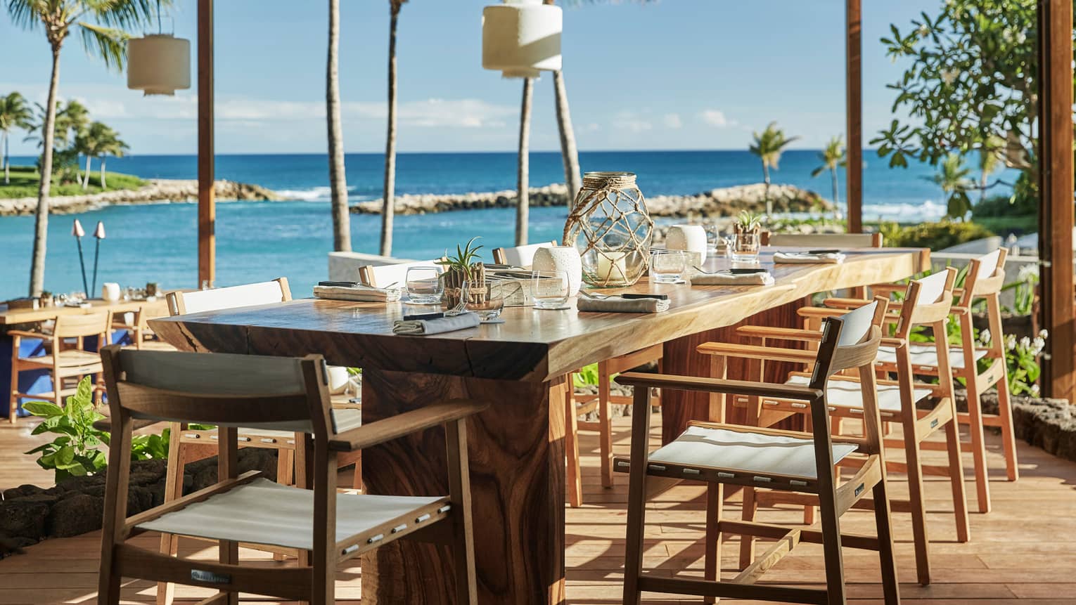 Long wood dining table with canvas chairs, rustic fishing-themed lanterns, candles