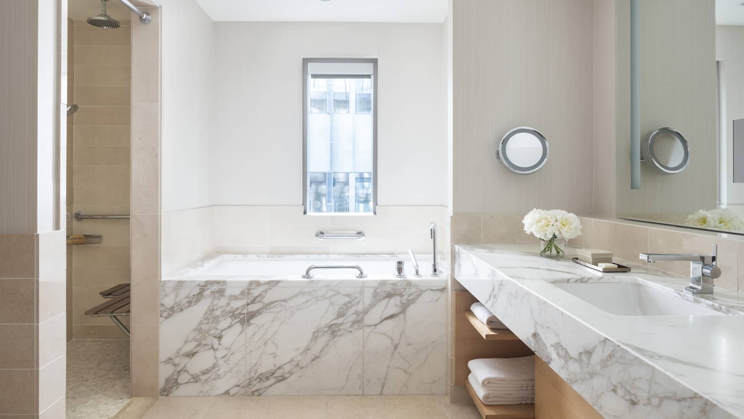 A bright bathroom has a marble countertop and bath