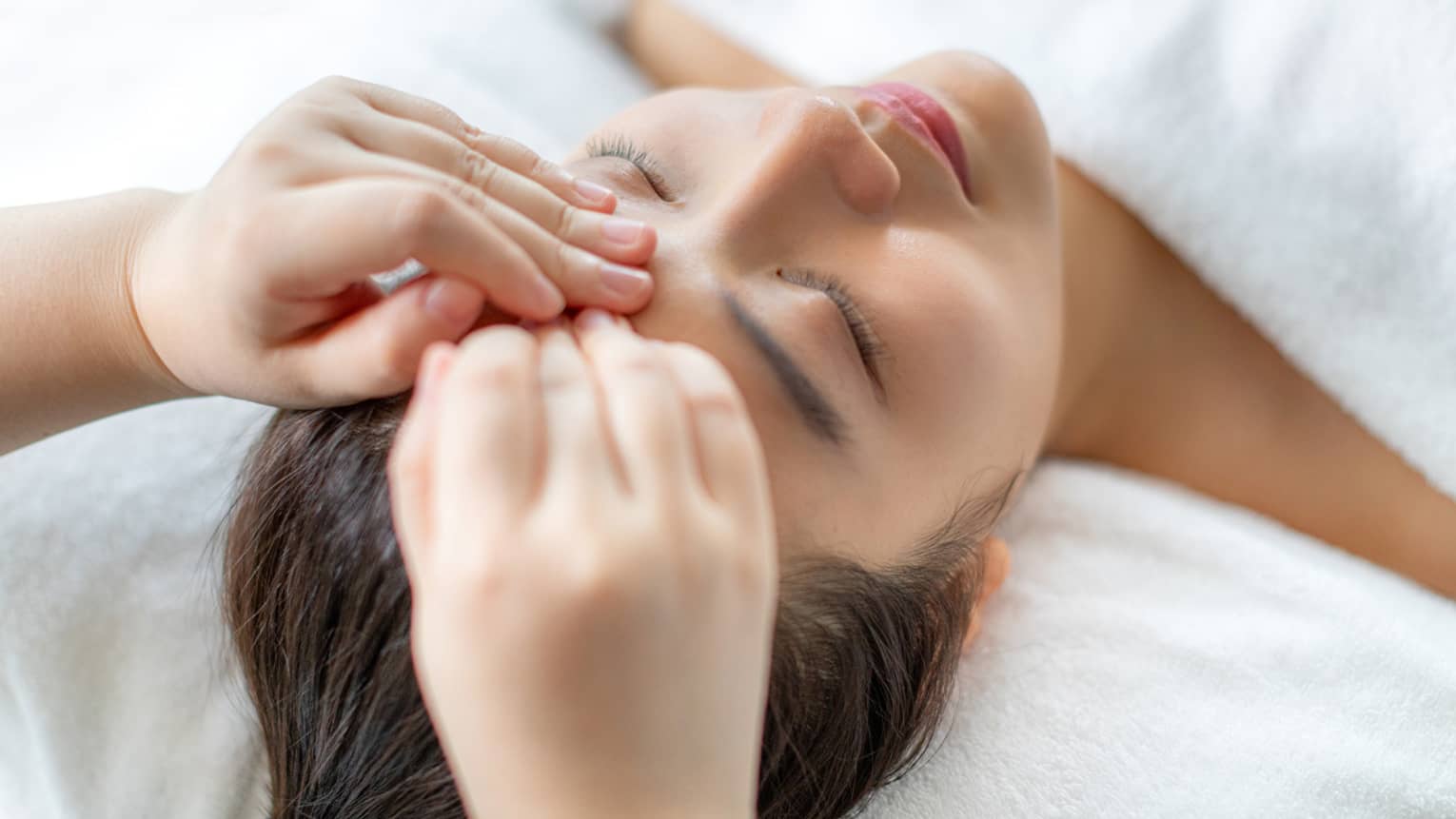 A woman getting a facial massage in a spa.