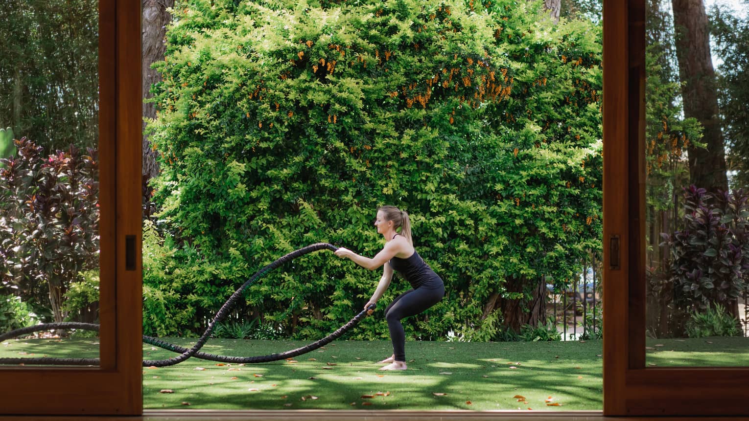 A woman does rope exercise outside on grass