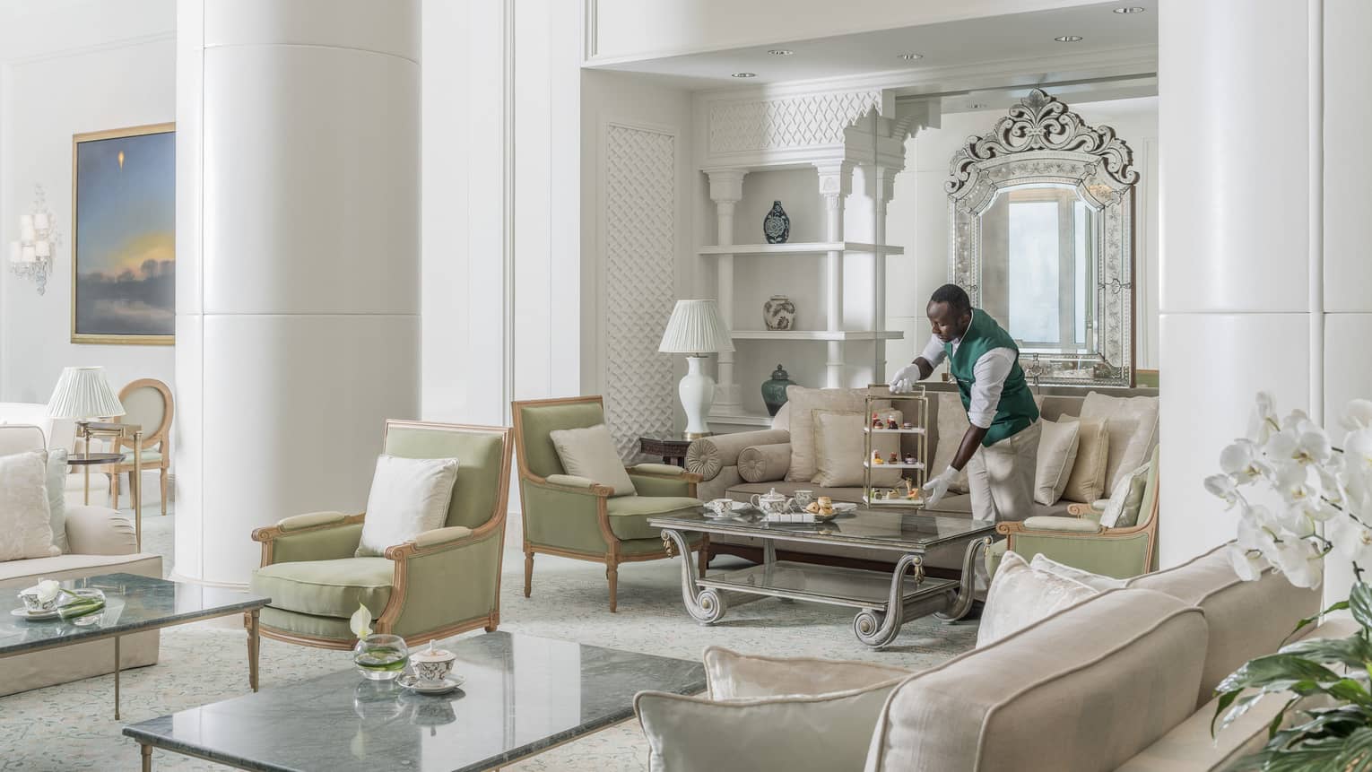 Interior of Seasons Tea Lounge featuring white walls, tall ceilings, light-green arm chairs, cream-colored sofas and rectangular glass tables