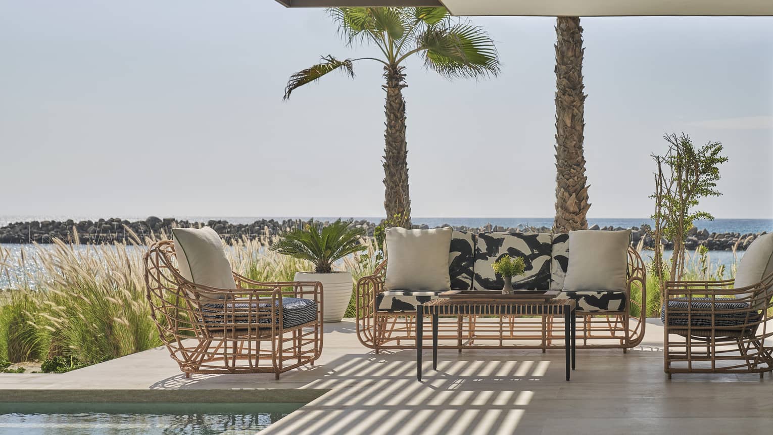 Two Bedroom Sunrise Suite pool, two rattan arm chairs and sofa, palm trees, ocean views