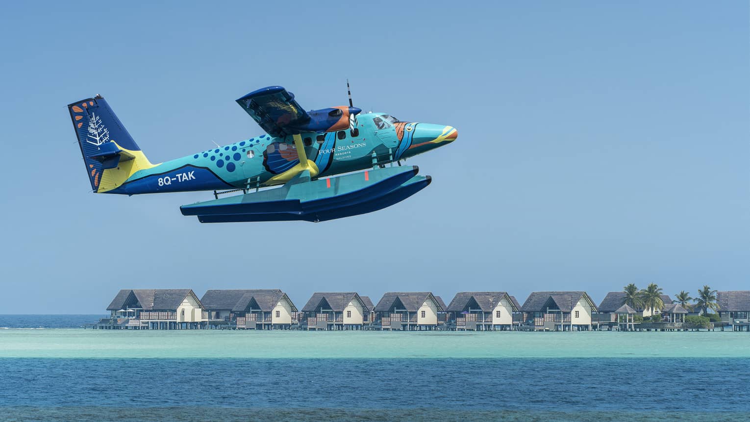 Maldives Sea Plane taking off with water villas and palm trees in the background