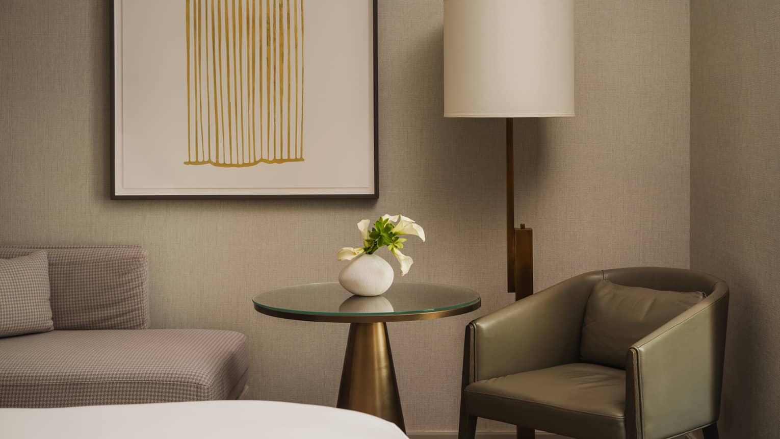 A modern hotel room detail, featuring a round table and a green leather arm chair for dining or leisure
