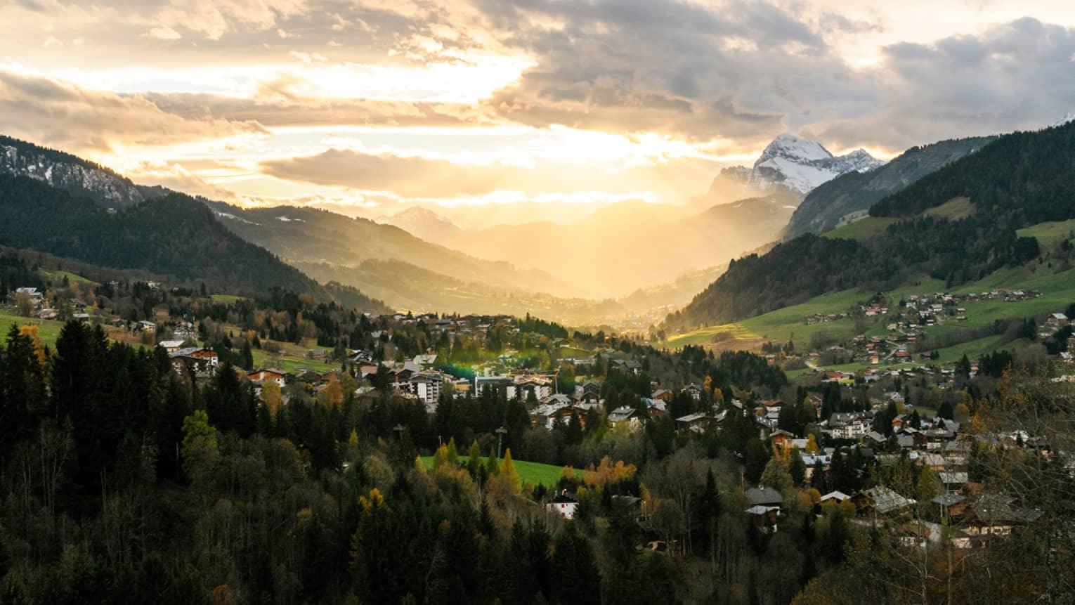 Panoramic view over rolling French Alps at sunset, village nestled in mountains
