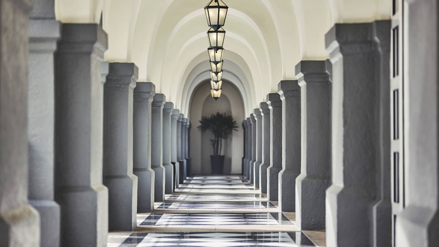 Stone pillars, lanterns down long, sunny outdoor hallway
