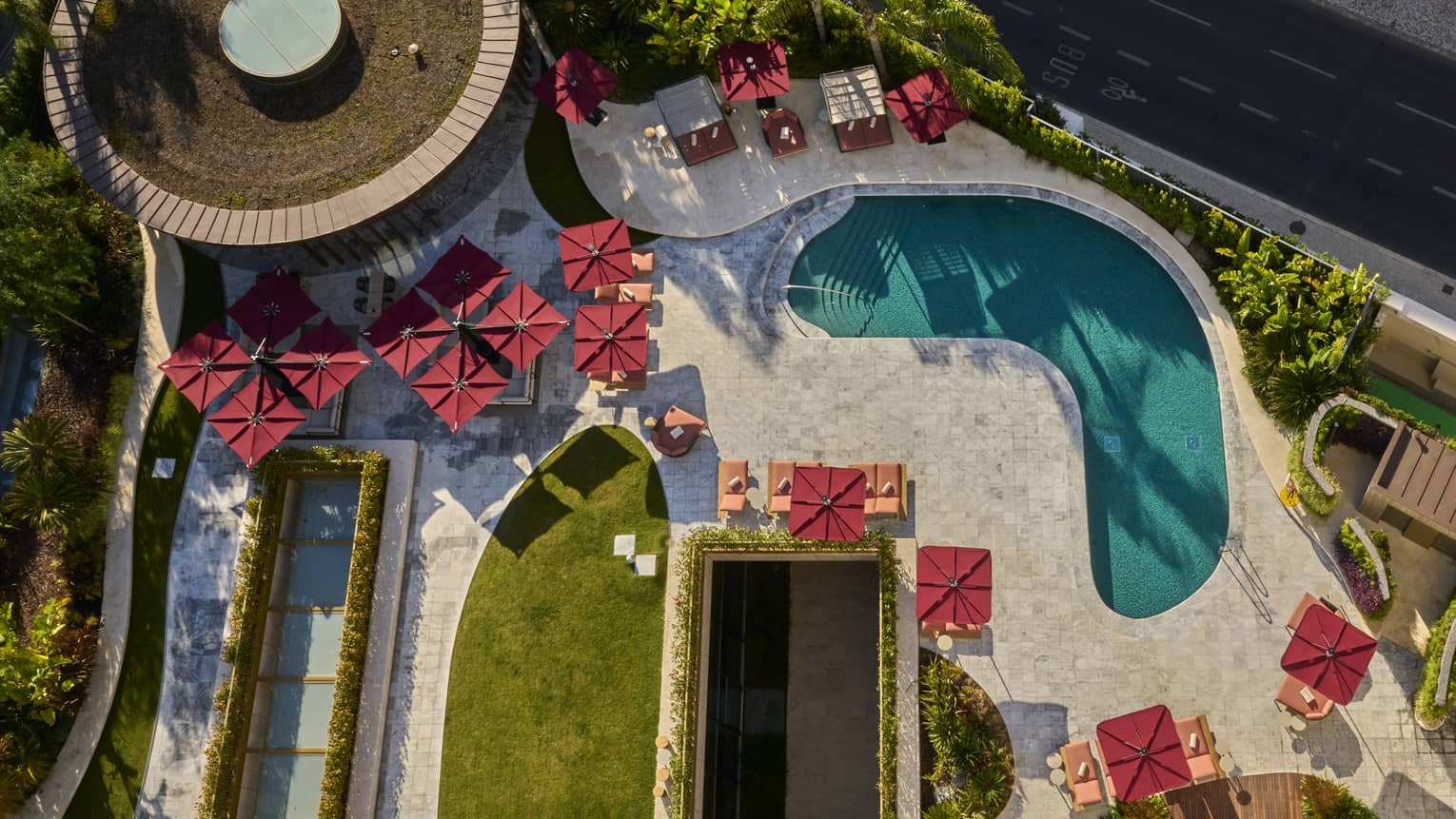 Aerial view of kidney-shaped pool surrounded by red umbrellas