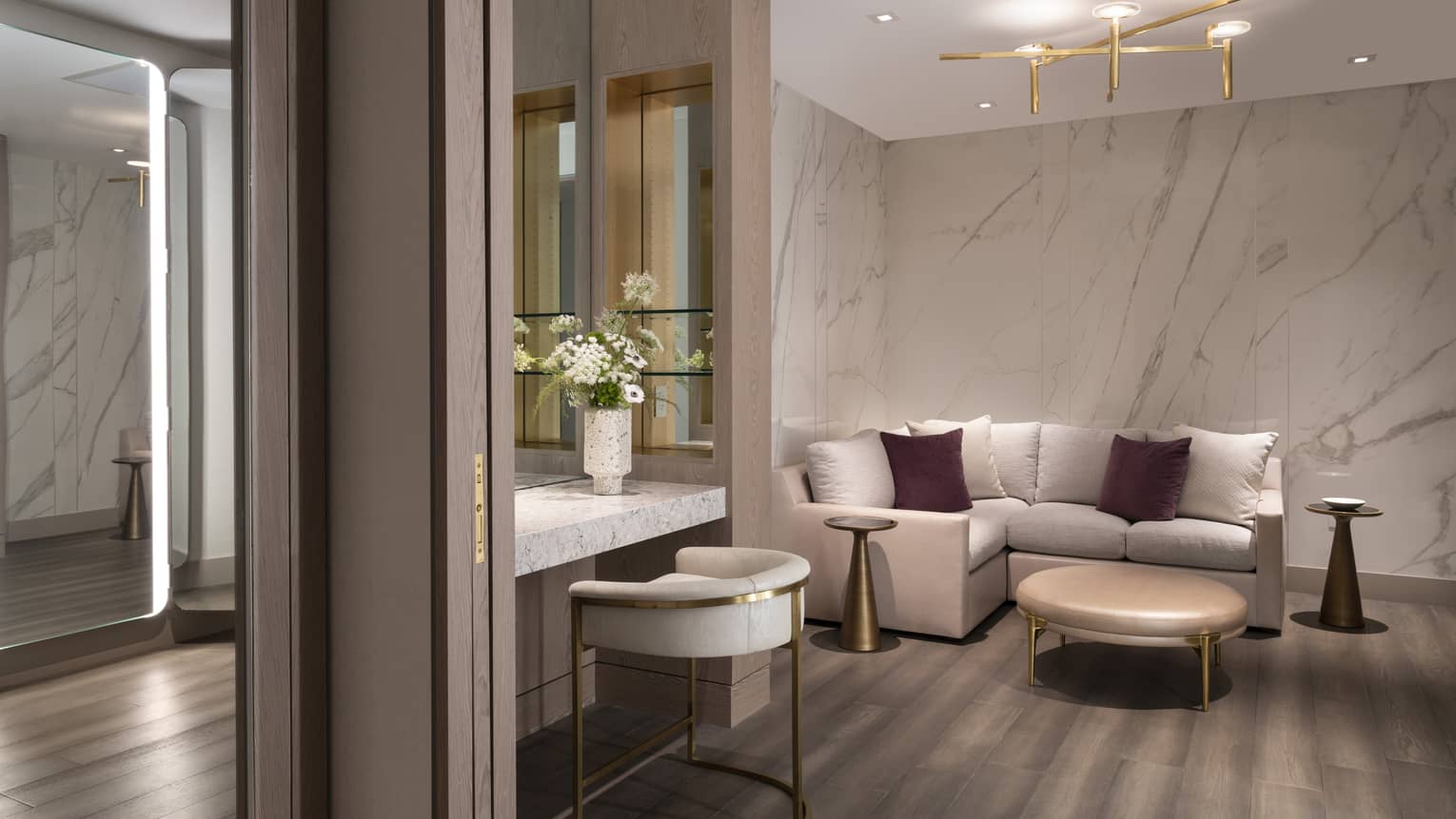 An L-shaped couch, coffee table, mirrors and vanity table fill a corner of the Celebration Suite