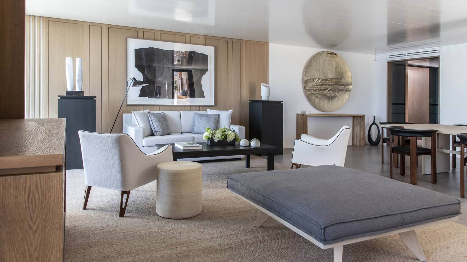 Beach-chic living room with a sofa, two arm chairs, a large ottoman with a grey cushion