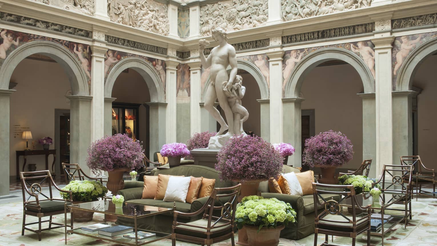 Il Palazzo lobby, sunny atrium with stone statue on pedestal over seating area, purple flowers