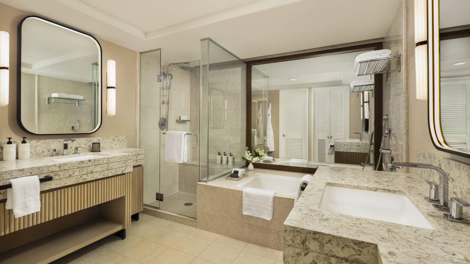 Hotel room bathroom featuring sunken tub, separate glass shower and a sink vanity on each side of the bathroom