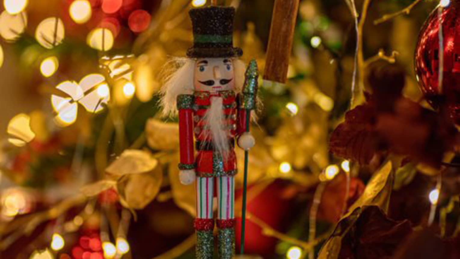A nutcracker ornament on a Christmas tree.