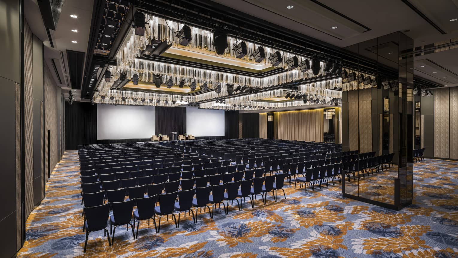 Rows of chairs set up facing stage with white backdrop for event in Grand Ballroom 