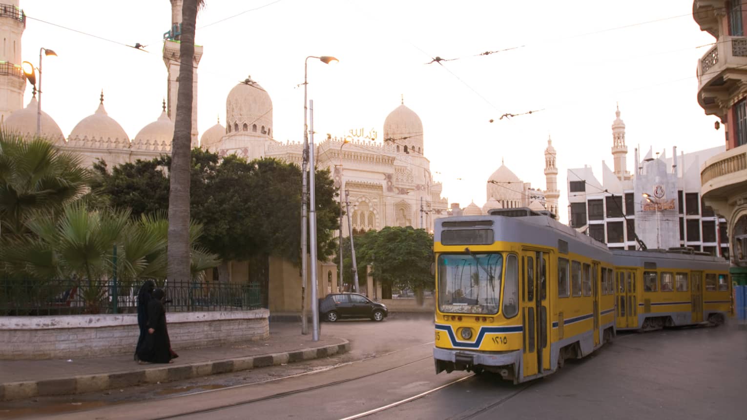 Yellow trolley car on track in front of El-Mursi Abul Abbas Mosque on sunny day