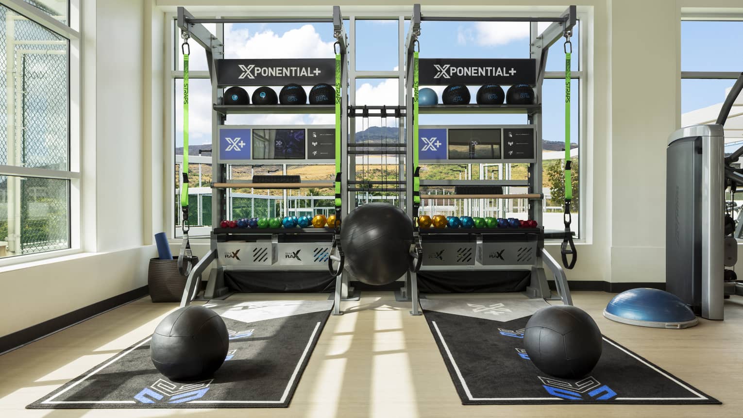 Two exercise stations with mats, kettle balls and TRX in light-filled luxury resort gym